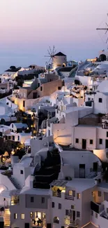 Santorini's white buildings at twilight, glowing under a calming sky.