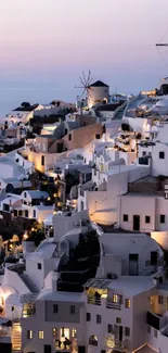 Santorini's nightscape with white buildings and sunset hues.