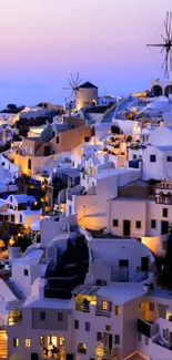 Santorini white buildings at sunset with blue domes and windmills.