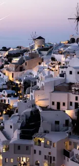 Santorini's white buildings at twilight with windmills.