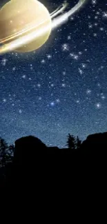 Saturn in a starry night sky over silhouetted landscape.