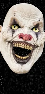 Terrifying clown mask on black background wallpaper.