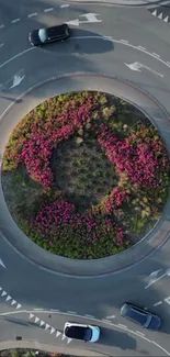 Aerial view of roundabout with vibrant flowers and cars.