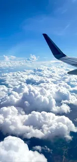 Airplane wing soaring above white clouds against a bright blue sky.