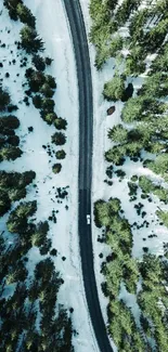 Aerial view of a snowy forest with a winding road.