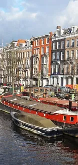 Amsterdam canal with boats and historic buildings under a blue sky.