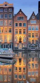 Amsterdam canal houses reflected in water, creating a picturesque evening scene.