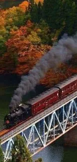 Steam train crossing a bridge through vibrant autumn scenery.