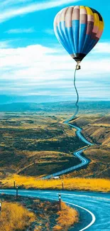 Hot air balloon over winding road with blue sky background.