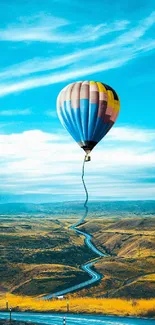 Hot air balloon over vast landscape with blue sky.