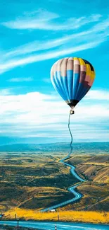 Vibrant hot air balloon soaring over scenic landscape under a bright blue sky.