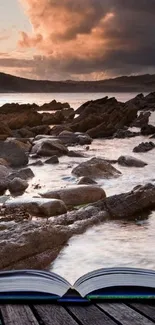 Open book on a dock with coastal sunset and rocks in the background.