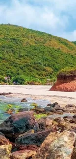 Scenic beach landscape with rocky coastline and greenery under blue sky.