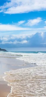 Scenic coastal view with blue sky and ocean waves on a sandy beach.