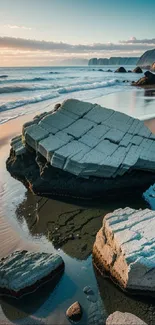 Rocky beach at sunrise with ocean waves.