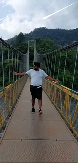 Man walking on scenic bridge with green mountains.