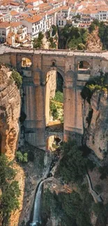 A breathtaking view of a stone bridge over a canyon with waterfalls and a town in the background.