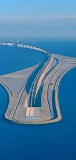 Scenic bridge extending over a calm blue ocean in a clear natural setting.