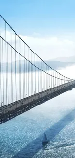 Tranquil bridge over misty water with sailboat and blue sky background.