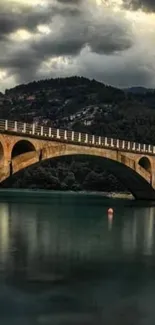 Scenic bridge under a dramatic stormy sky with mountain backdrop.