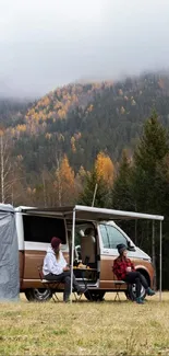 Camper van with a scenic mountain view and forest in autumn colors.