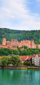 Historic castle overlooking a serene river with green hills and blue sky.