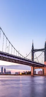 Beautiful city bridge and skyline at dusk, reflecting on calm river water.