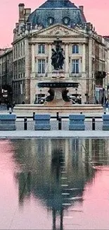 Elegant city building reflected in calm pink-hued waters at dawn.