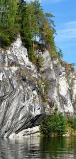 Scenic cliffside with lake and trees under a clear blue sky.