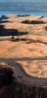 Breathtaking aerial view of a clifftop road winding through golden landscapes.