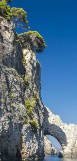 Coastal arch against a clear blue sky with calm waters.