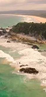 Emerald coastal waves with rocky cliffs and sandy beach background.