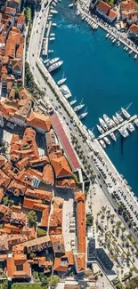 Aerial view of a coastal city with yachts and terracotta rooftops.