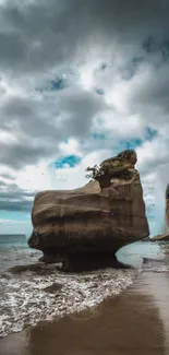 A stunning rock formation on a tranquil beach under a dramatic cloudy sky.