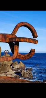 Rusty coastal sculpture with blue sea and sky.