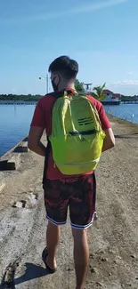 Man with backpack walking along a sunny coastal path.