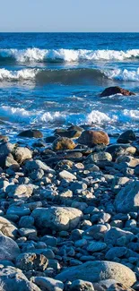 Rocky beach with waves crashing on the shore under a clear sky.