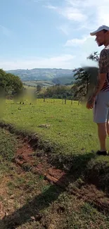 Man walking in a lush green meadow under cloudy skies.