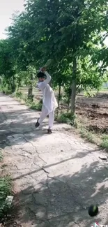 Person playing cricket on a green pathway under trees.