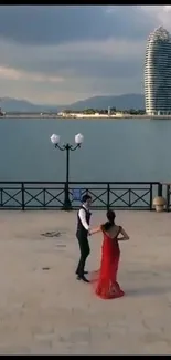 Couple dancing by waterfront with modern towers.