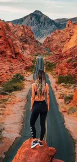 Woman on desert road surrounded by red rocks.