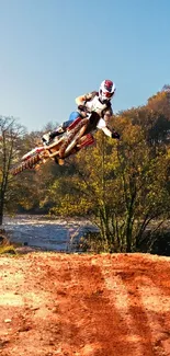 Dirt bike jumping through scenic autumn landscape.