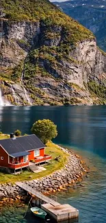 Idyllic fjord cottage with mountain and waterfall backdrop.