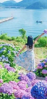 Woman in dress with hydrangeas overlooking lake.