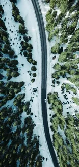 Aerial view of a winding road through a snowy forest landscape.