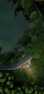 Aerial view of car on scenic forest road by the lake.