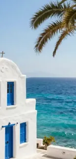 White house with blue windows by the sea and palm tree on a Greek island.