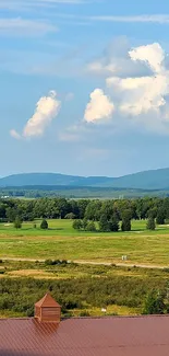 Lush green fields under a blue sky with distant mountains.