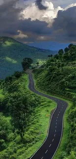 Winding road through lush green mountains under dramatic skies.