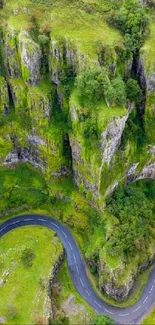 Aerial view of a scenic green valley with a winding road and lush cliffs.